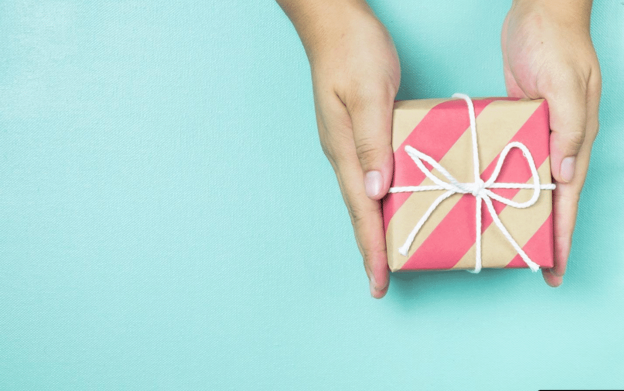 hands holding a gift wrapped in brown paper