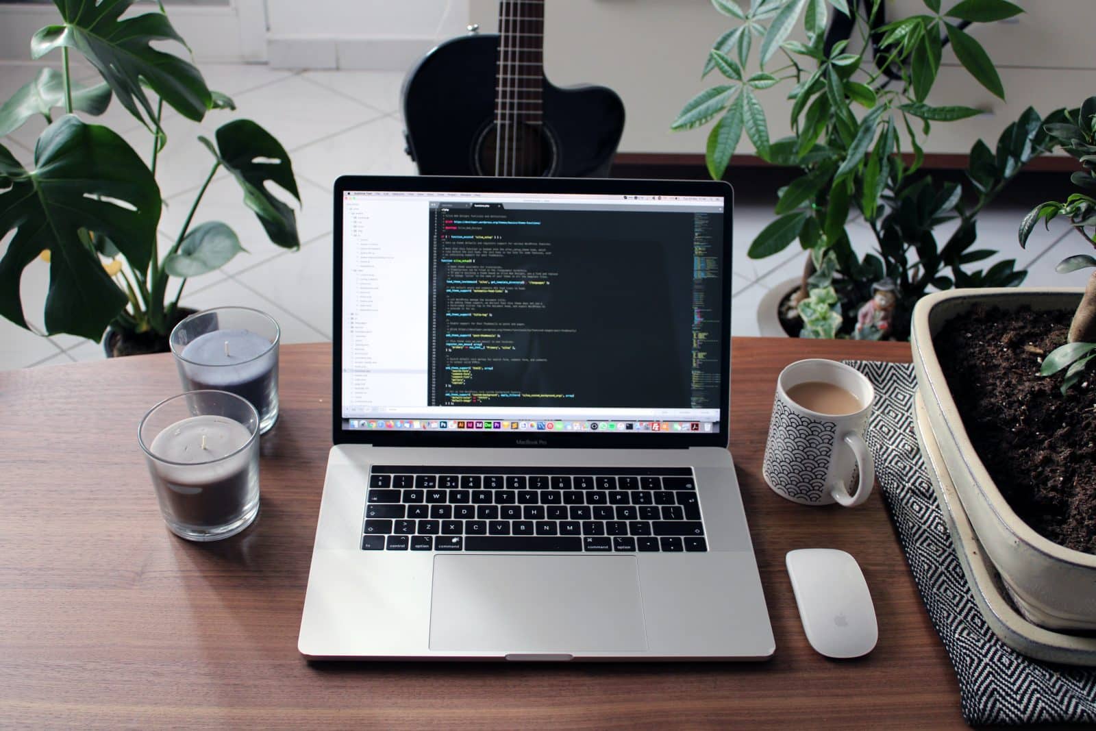 macbook pro beside white ceramic mug on brown wooden table